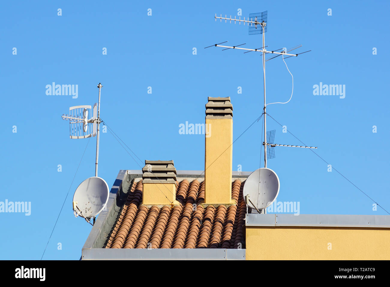 Satellite antenna and old roof antenna on a red roof . Stock Photo