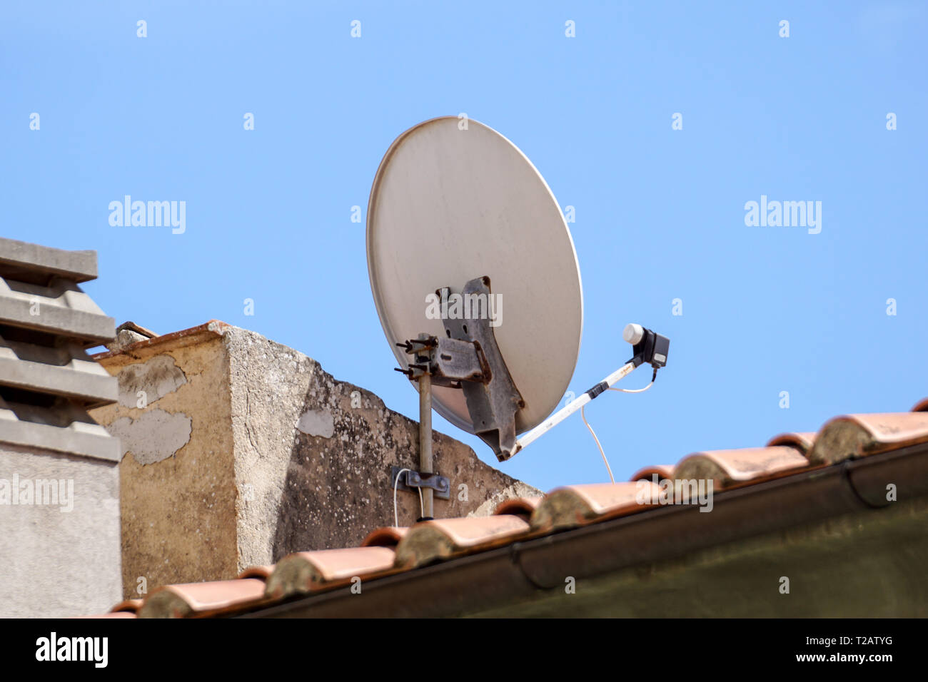 Satellite dish antenna mounted on the wall of a private house on blue sky background . Stock Photo