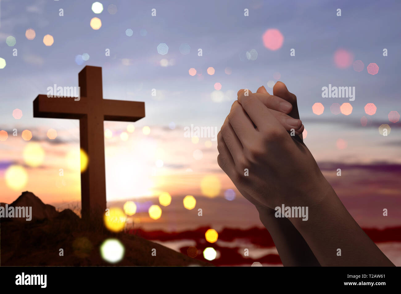 Christian cross and male hands with praying position over sunset background  Stock Photo - Alamy