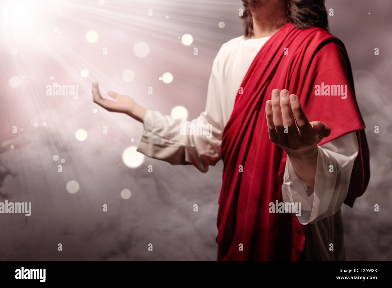 Jesus christ raised hands and praying to god with ray over blurry