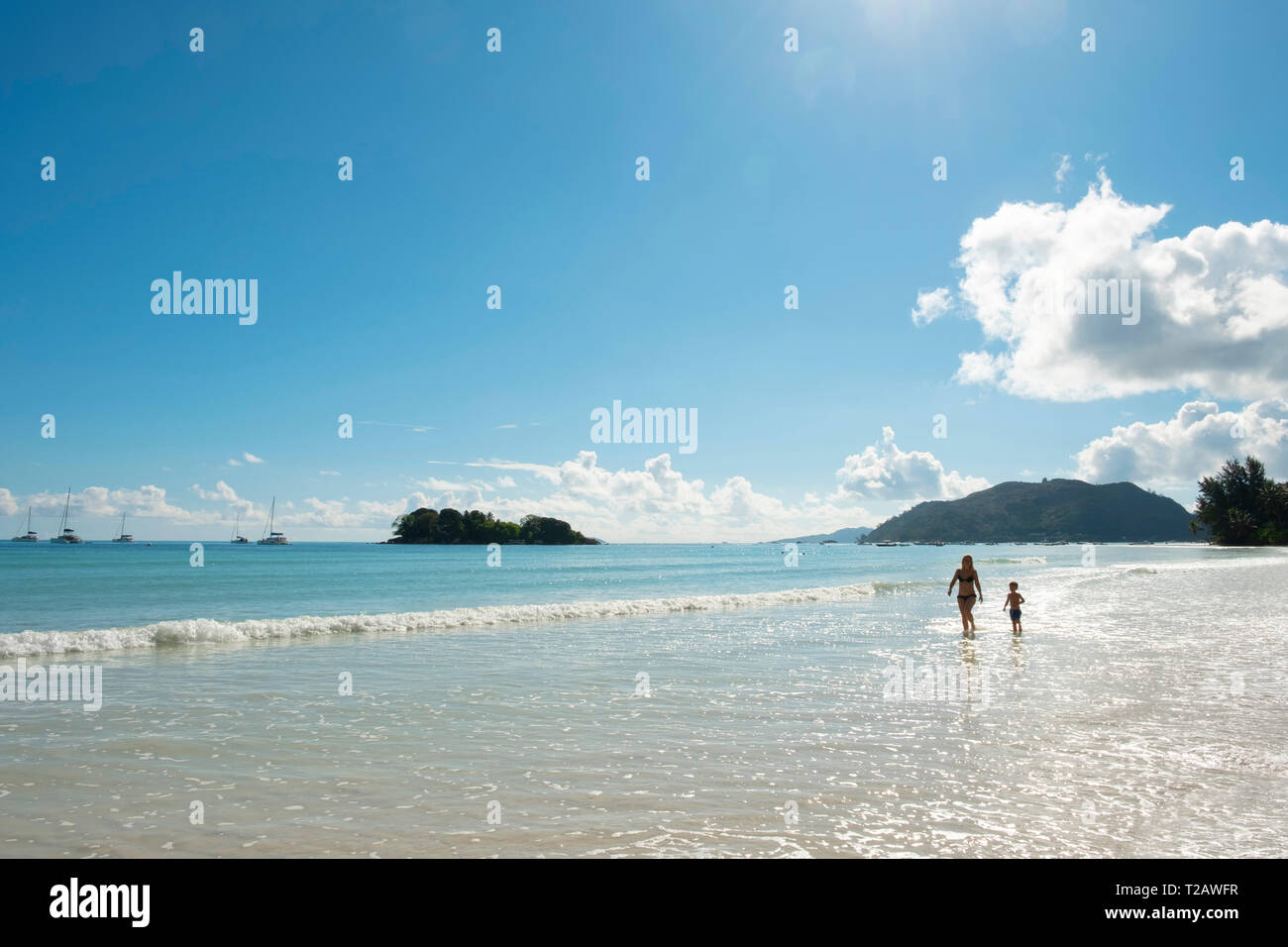 A mother and son walking in the surf on Anse Volbert, Praslin, the Seychelles Stock Photo
