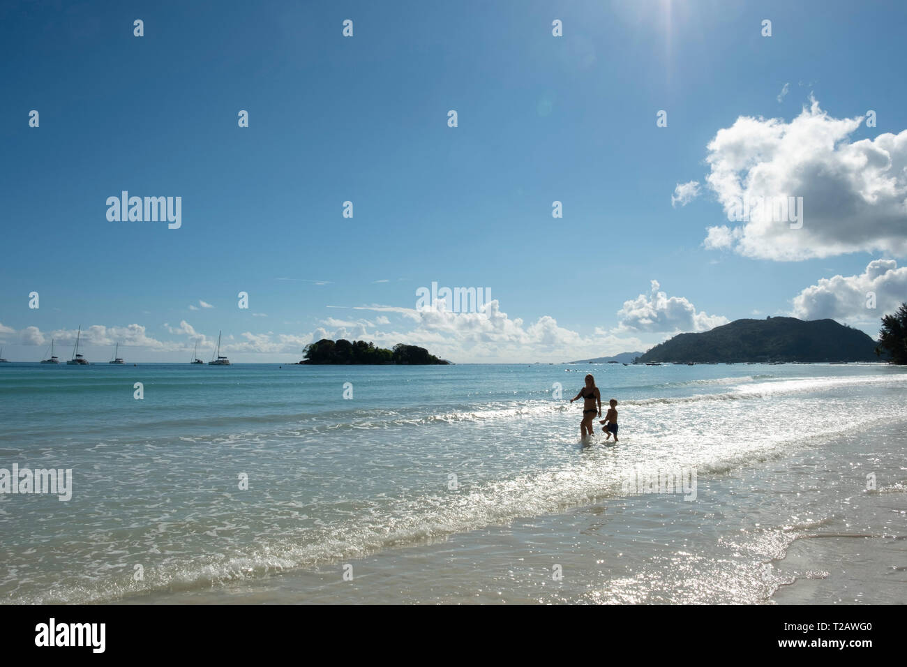 A mother and son walking in the surf on Anse Volbert, Praslin, the Seychelles Stock Photo