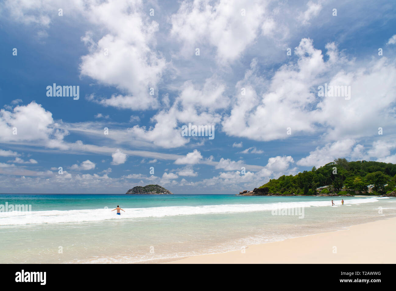People frolicing in the surf on Grand Anse on the west coast of Mahe, the Seychelles Stock Photo
