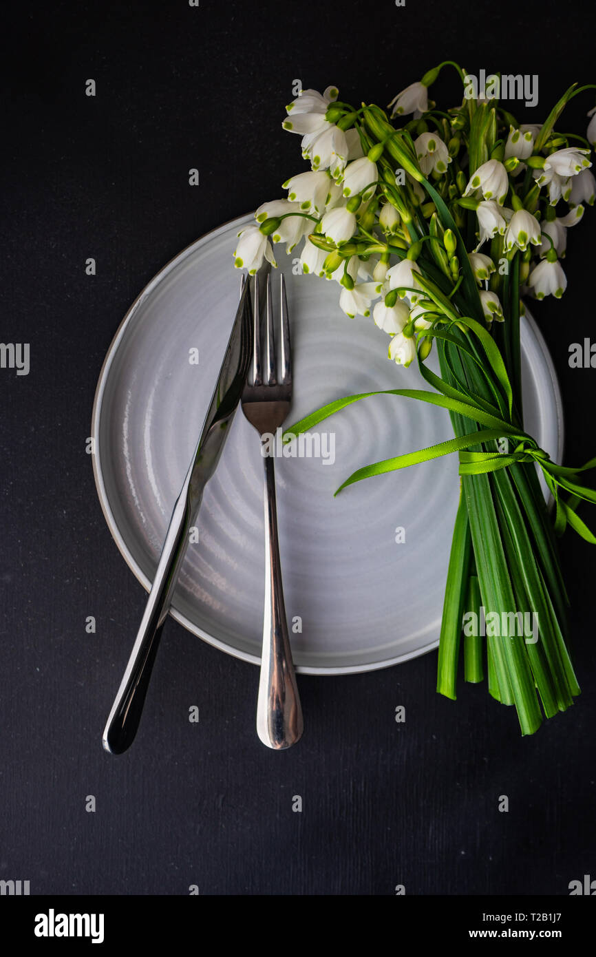 Feastive table setting for holiday Easter dinner decorated with spring snowdrop flowers on rustic table with copy space Stock Photo