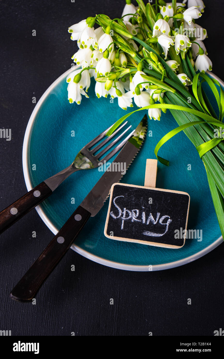 Feastive table setting for holiday Easter dinner decorated with spring snowdrop flowers on rustic table with copy space Stock Photo