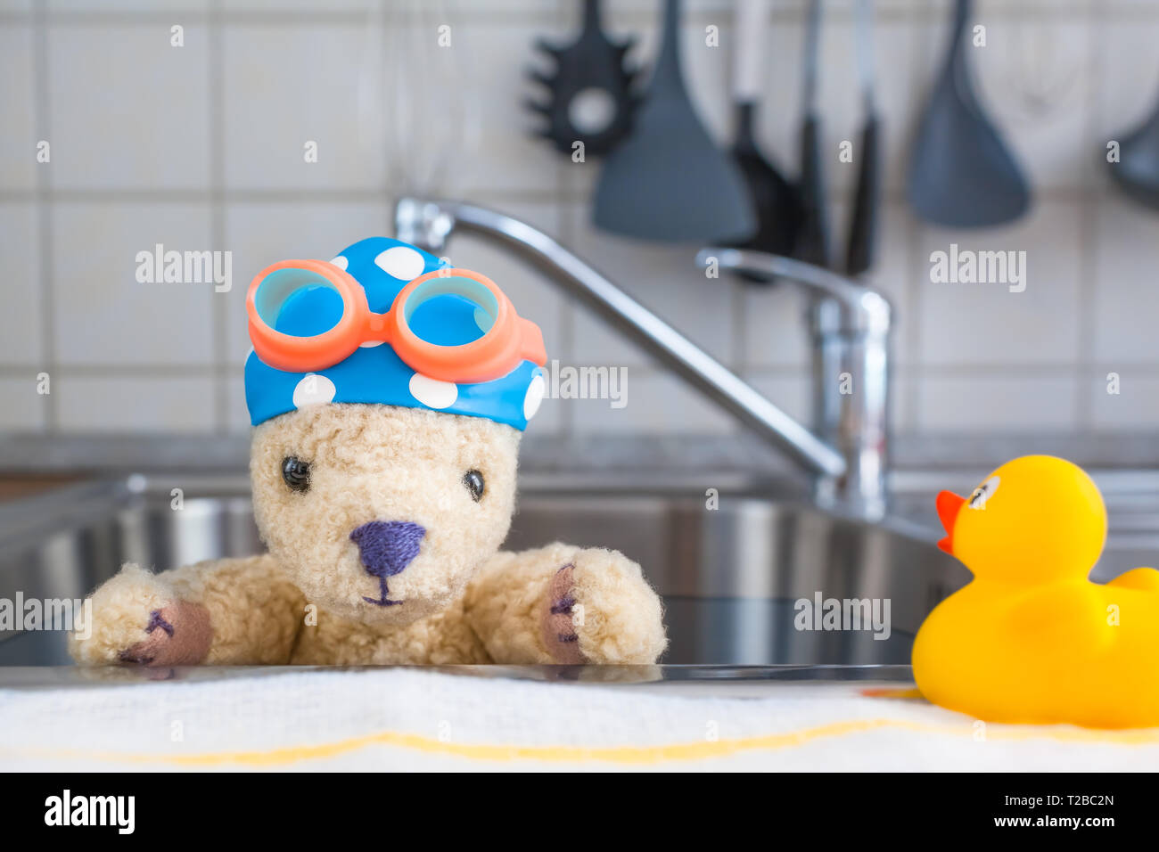 Kitchen stainless steel sink as swimming pool, cute toy teddy bear