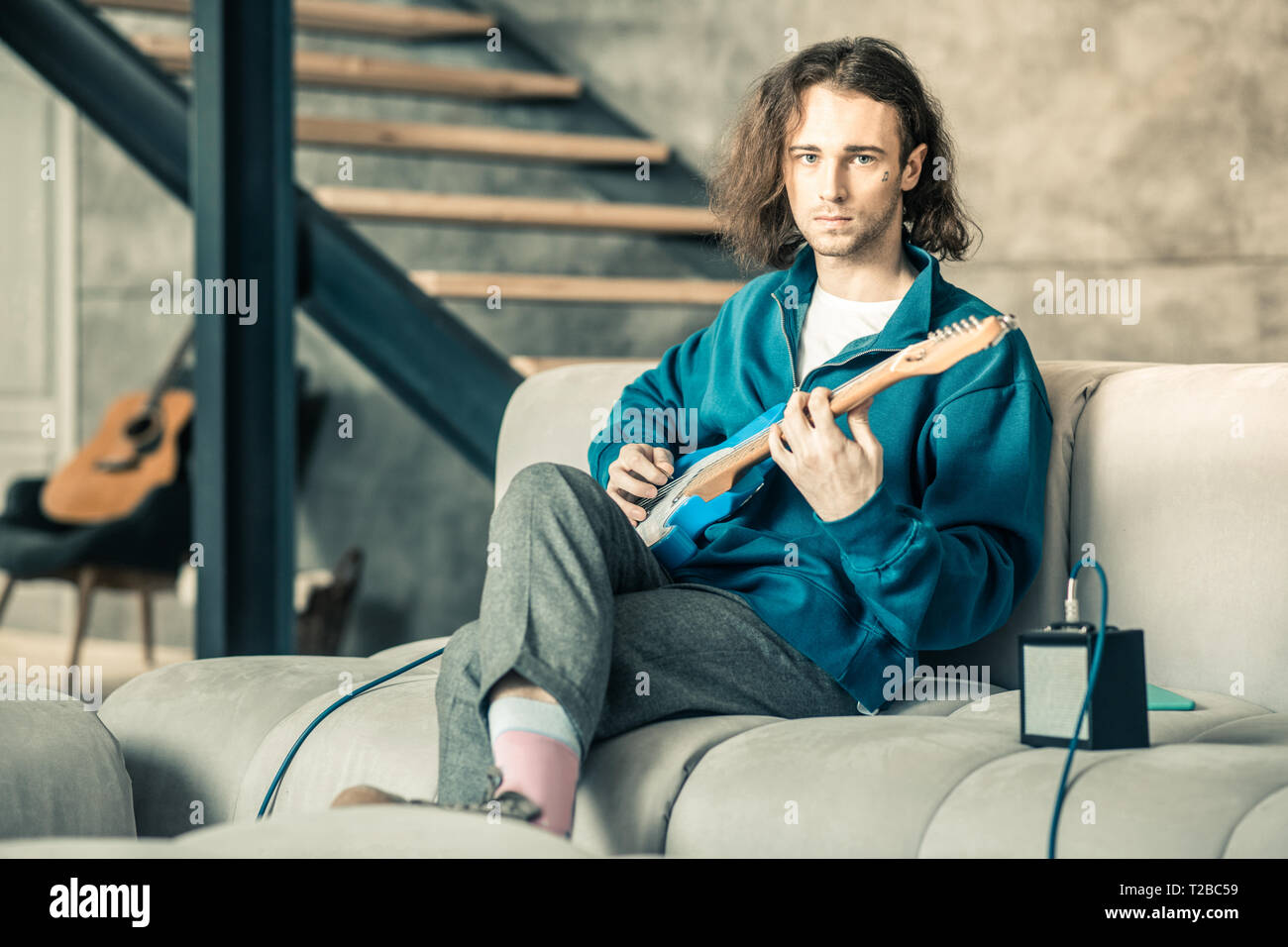 Handsome extraordinary man wearing stylish outfit while training his guitar skills Stock Photo