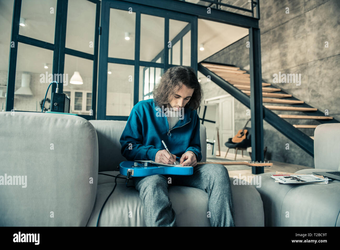 Focused dark-haired guy writing down notes in special album Stock Photo