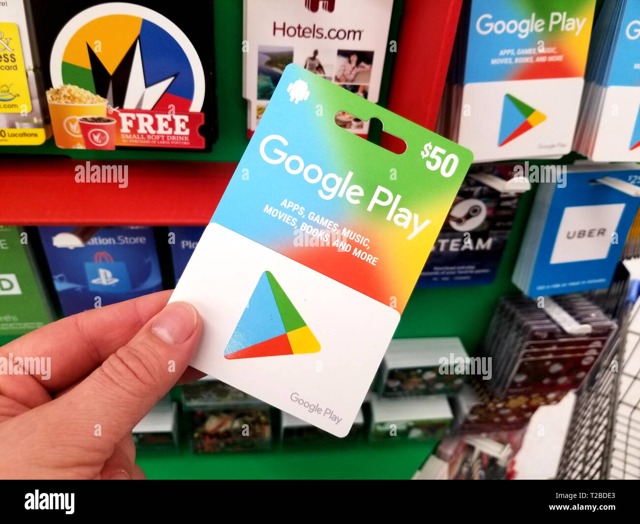 PLATTSBURGH, USA - JANUARY 21, 2019 : Google Play gift card in a hand over a shelves with different giftcards in a Walmart store. Stock Photo