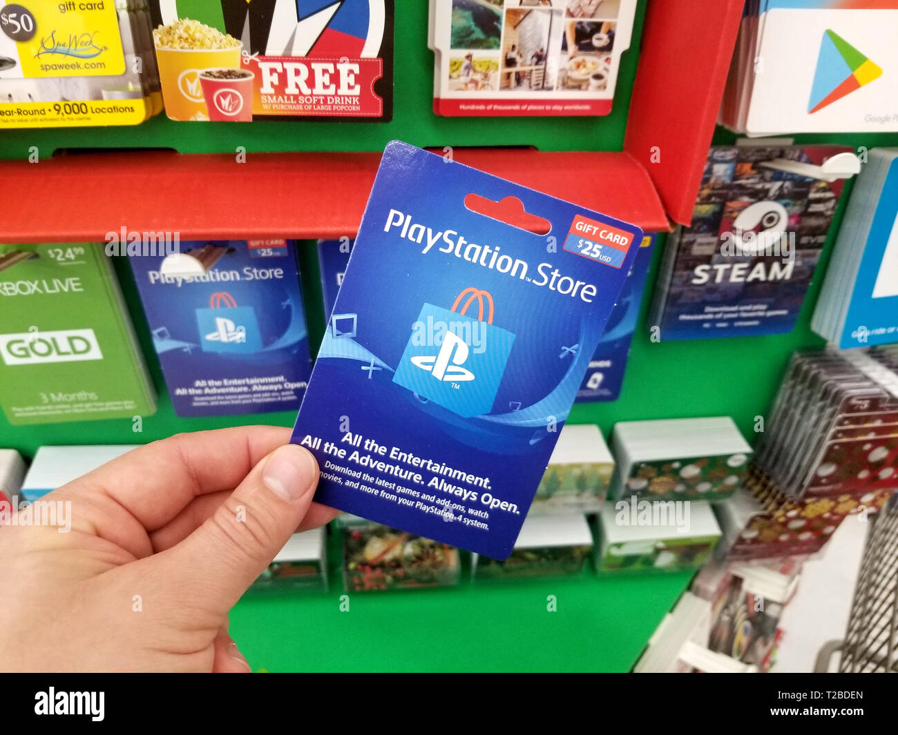 PLATTSBURGH, USA - JANUARY 21, 2019 : Play Station gift card in a hand over a shelves with different giftcards in a Walmart store. Stock Photo