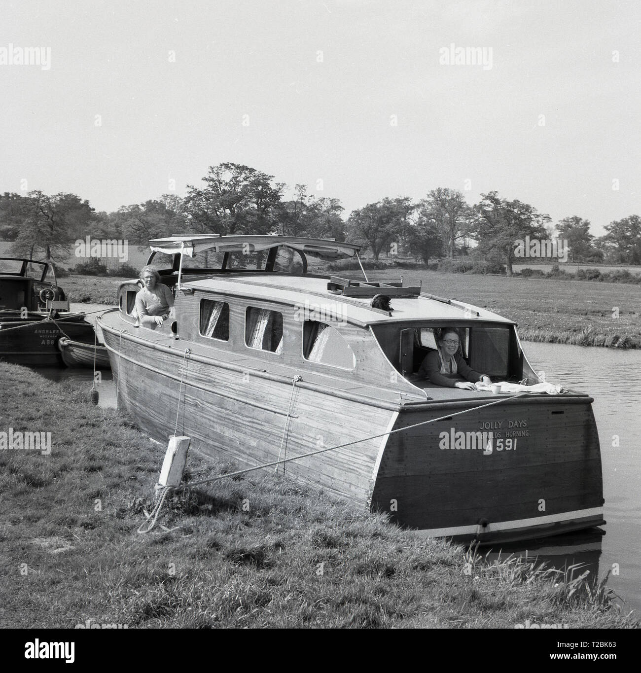 1950s, historical, two elderly ladies on their wooden built motor launch or cabin cruiser, 'Jolly Days', moored at the riverbank on the river Thames, near Oxford, England, UK. Stock Photo
