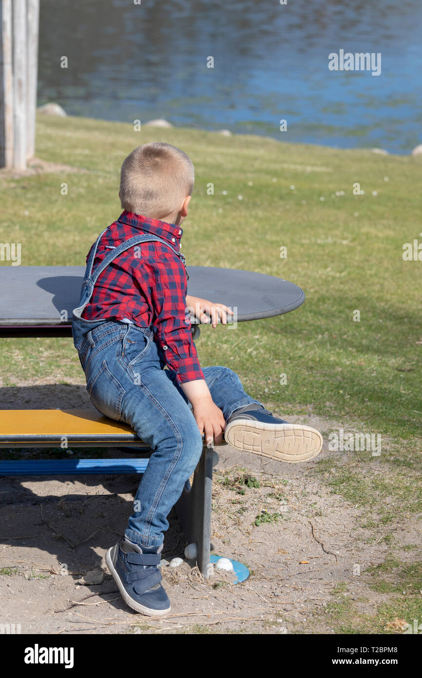 children sit on a wooden bench in the open air Stock Photo