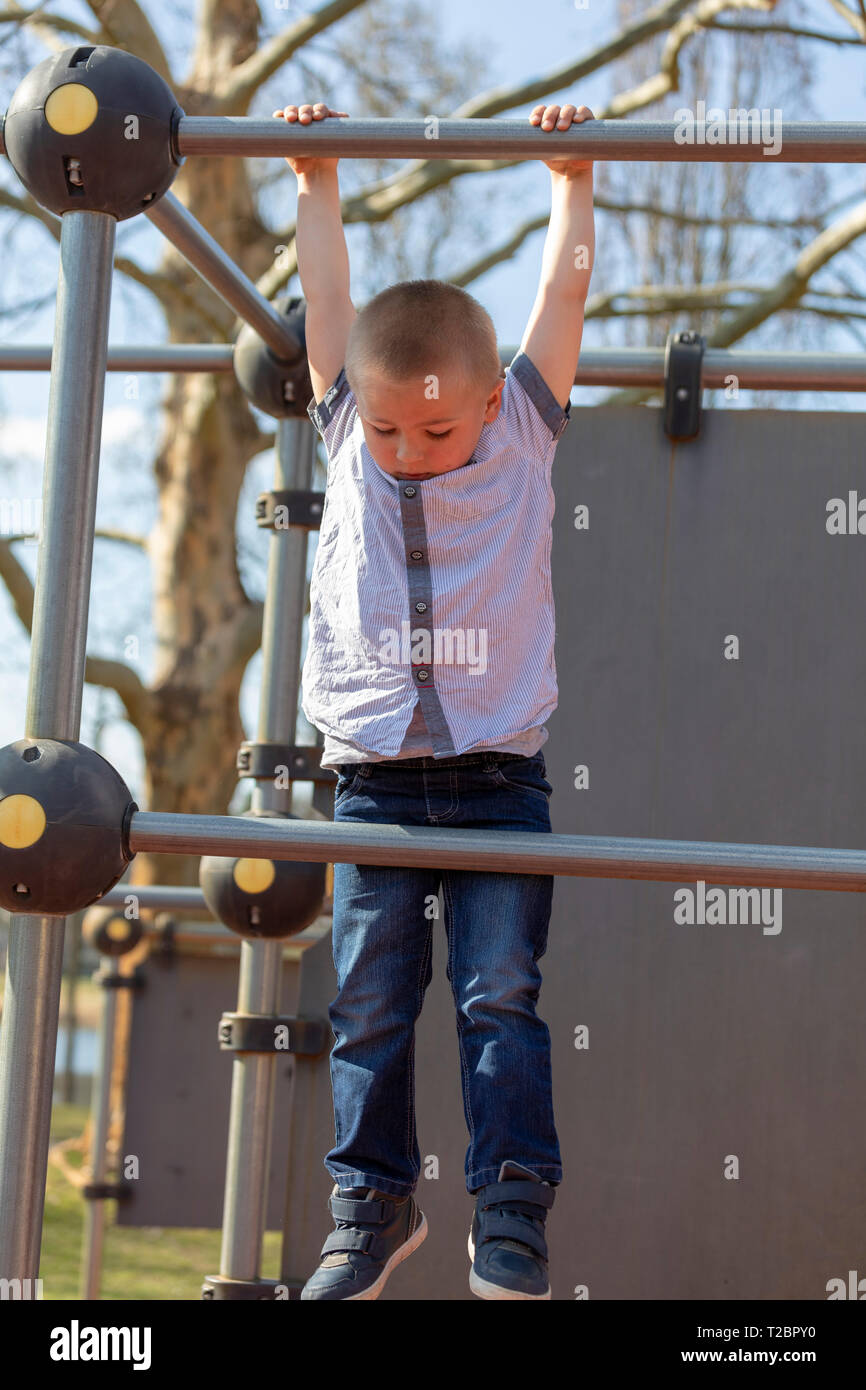 Little boy climbing on jungle gym without rope and helmet on playground