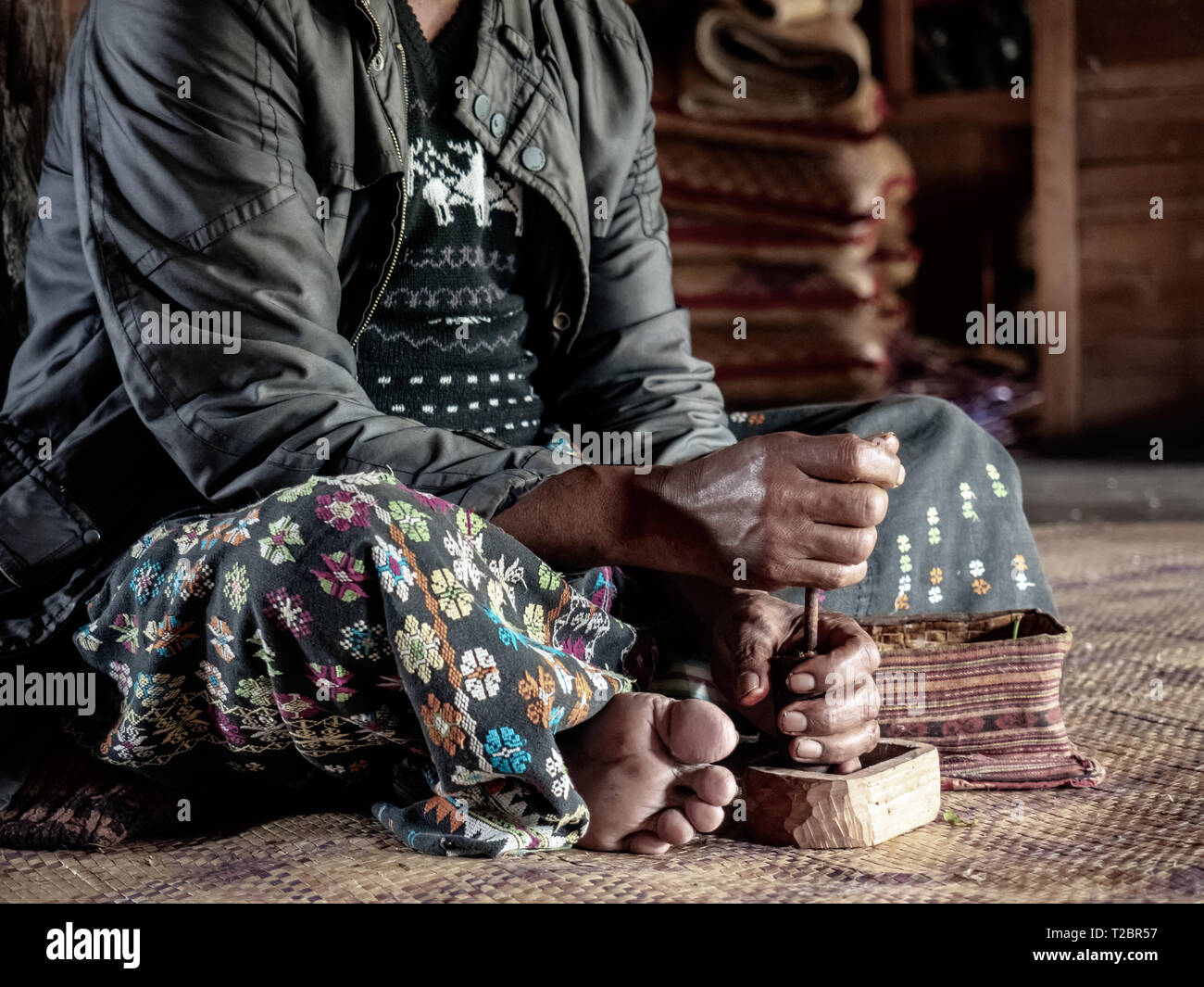 Asian old man sitting and pounding betel chewing leaves. Local ethnic village tribe member. Old Asian man in countryside, Indonesia shaman, shamanism Stock Photo