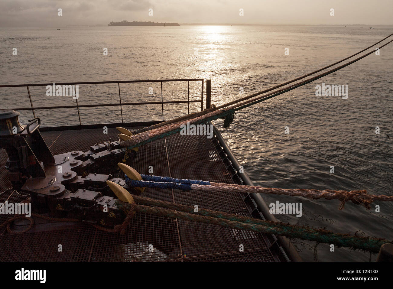 Port operations for managing and transporting iron ore. Sunrise across  Dolphin jetty mooring facility with quick release rope hooks as ship sets sail Stock Photo