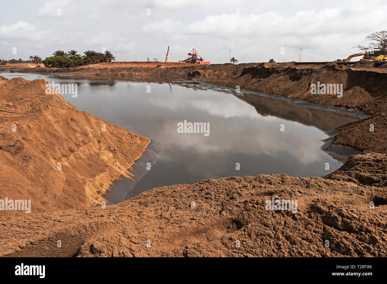 Port operations for managing and transporting iron ore. Future site extension with water area being reclaimed with sand from dredging sea channel Stock Photo