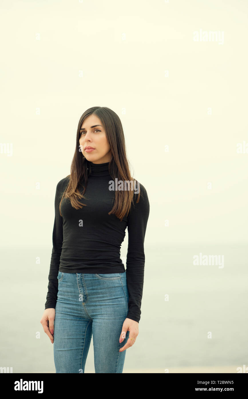 Beautiful woman standing on the beach looking away Stock Photo - Alamy