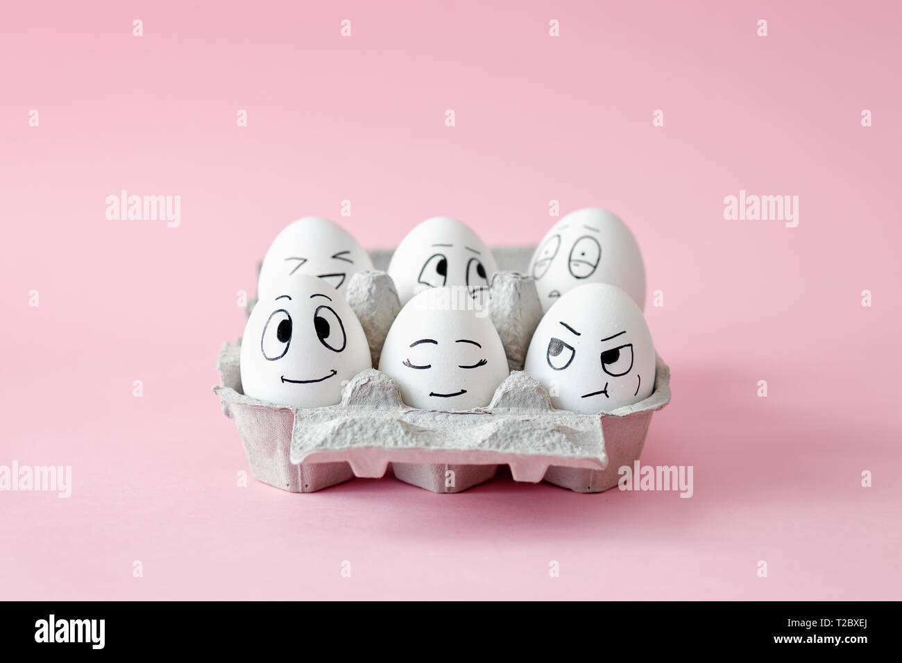 Funny Easter eggs with facial expressions. Eggs with different faces in egg carton. Stock Photo