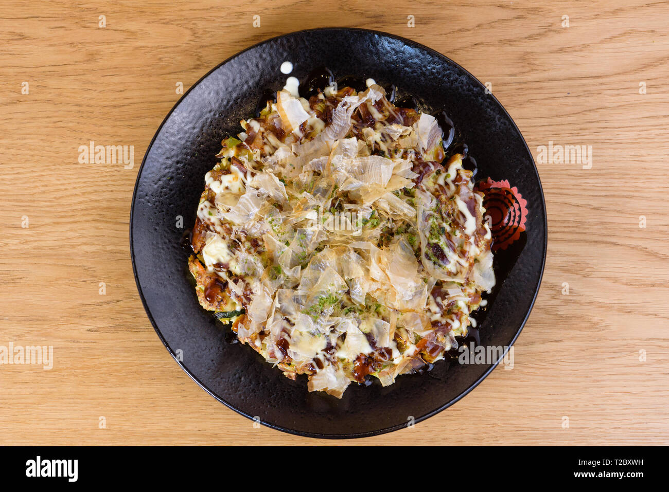 traditional Japanese omelette Okonomiyaki, with eggs, Savoy cabbage, mayonnaise, carrot, zucchini, ginger, dried seaweed and Katsuobushi, okaka, flake Stock Photo
