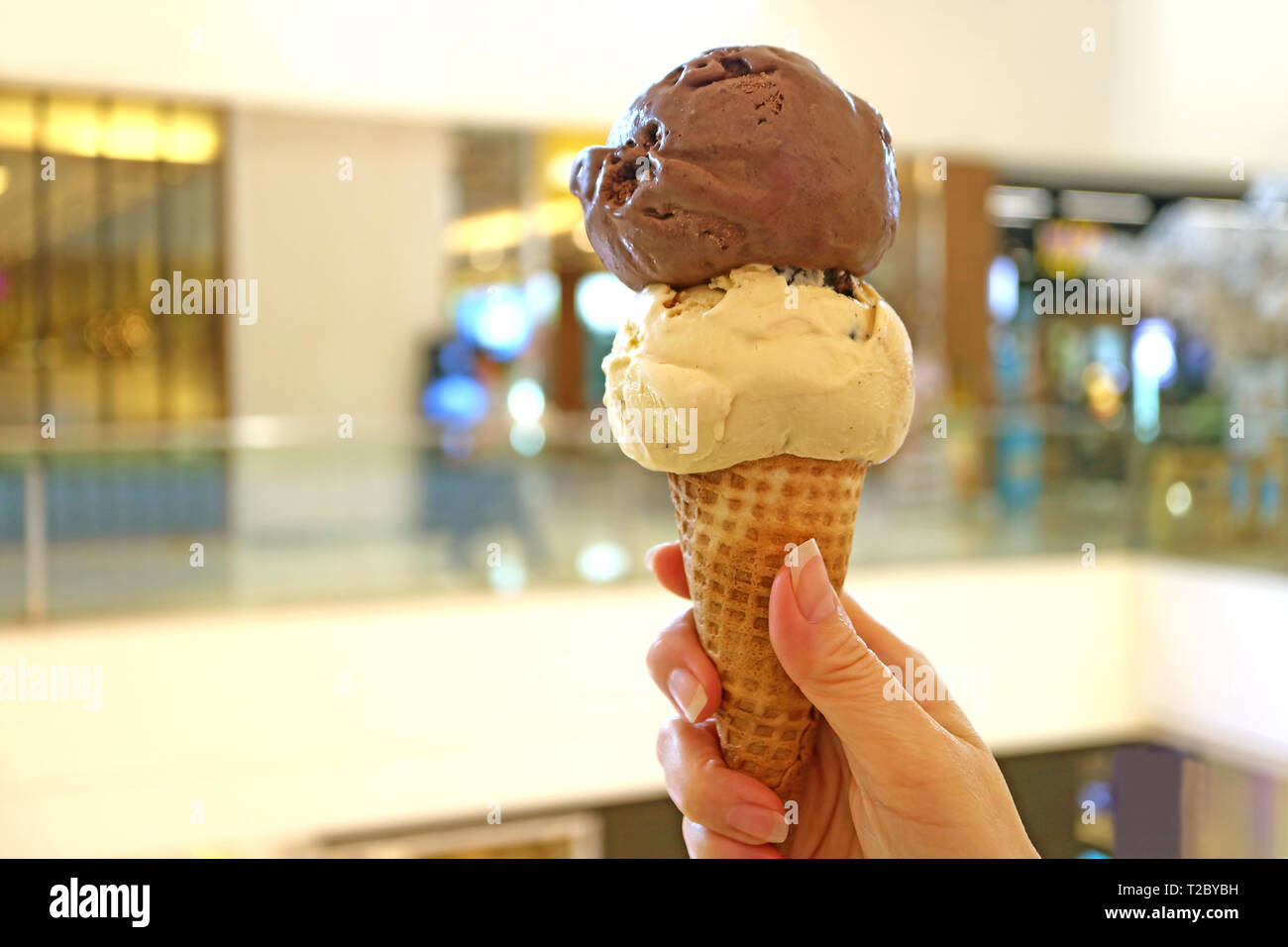 Two scoops of peanut butter and chocolate ice cream cone in woman's hand Stock Photo