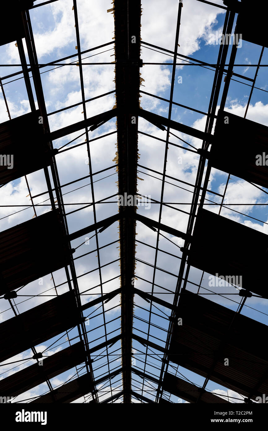 Sky with clouds seen from across the structure of an old roof. Can be used as background. Stock Photo