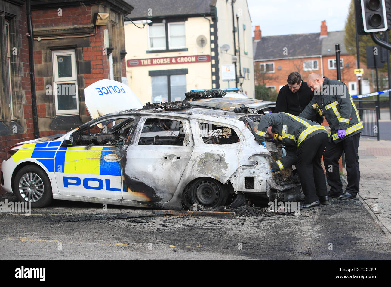 Fire fighters attend to two police cars that were destroyed after being set on fire outside Goldthorpe police station in South Yorkshire in a suspected arson attack. Stock Photo