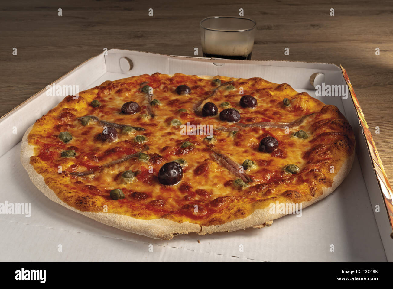 pizza pomodoro acciughe capperi olive nere intera nella scatola Stock Photo