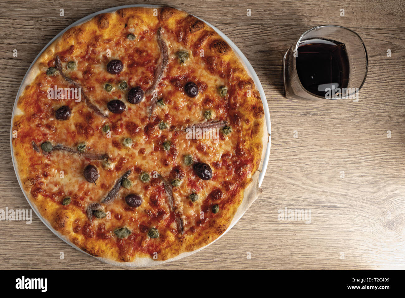 pizza pomodoro acciughe capperi olive nere intera dall'alto nel piatto Stock Photo
