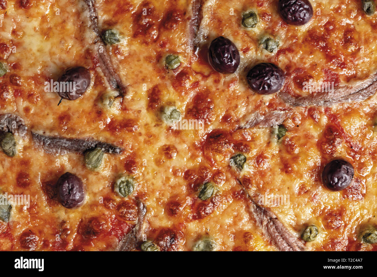 pizza pomodoro acciughe capperi olive nere intera primo piano texsture Stock Photo