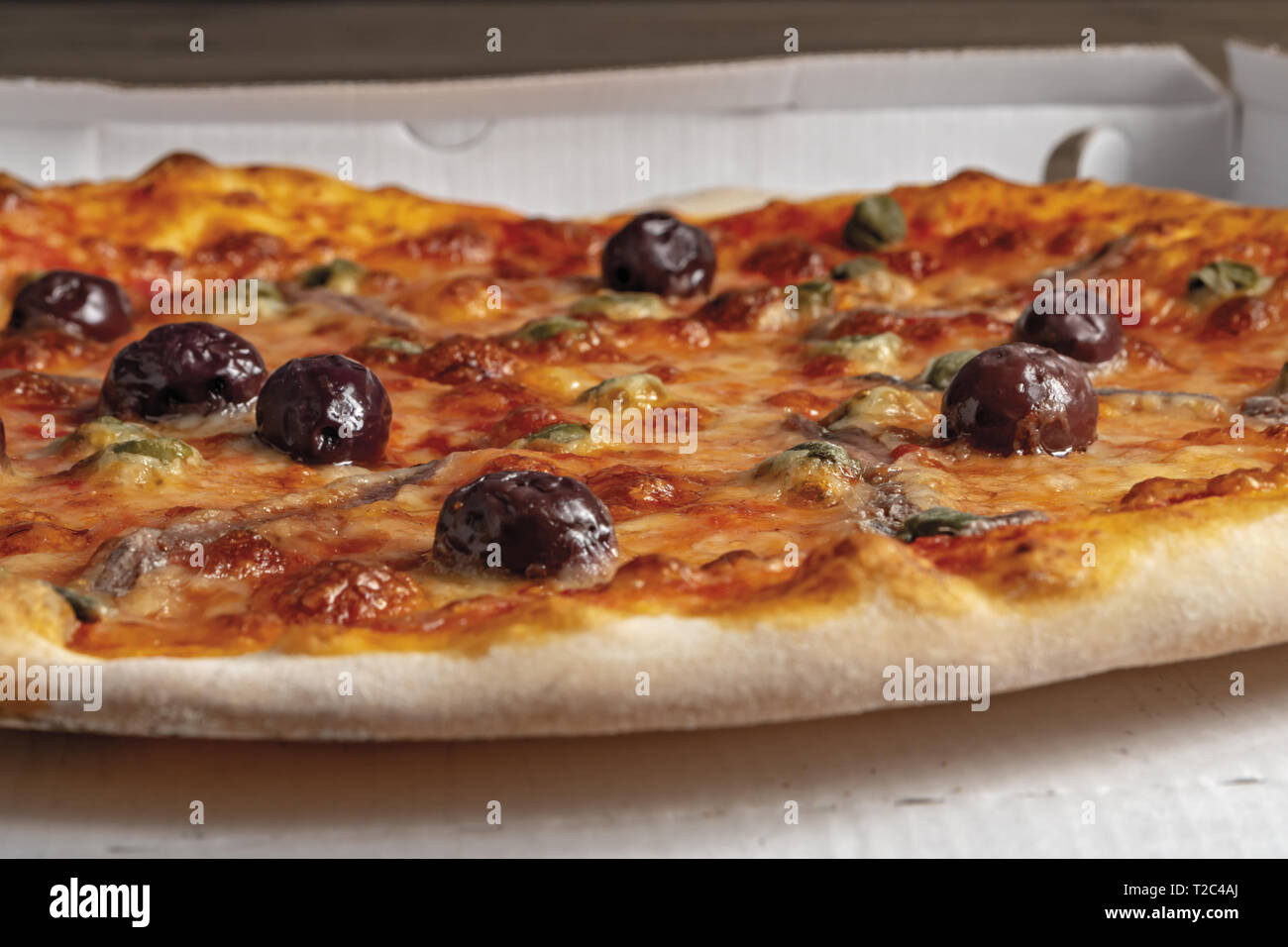 pizza pomodoro acciughe capperi olive nere intera nella scatola dal basso primo piano Stock Photo