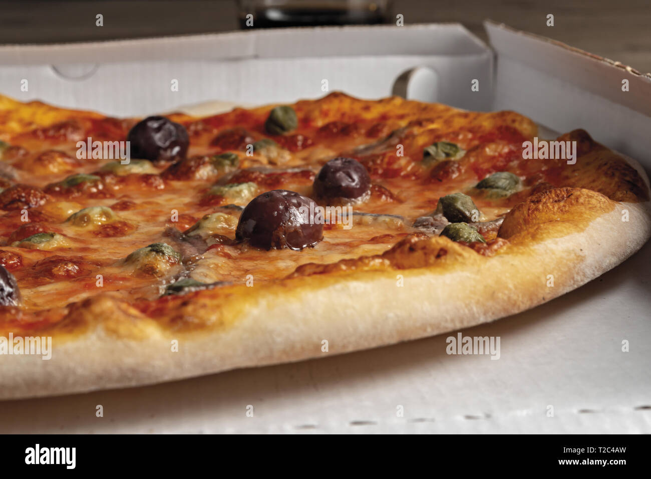 pizza pomodoro acciughe capperi olive nere intera nella scatola dal basso primo piano vista destra Stock Photo