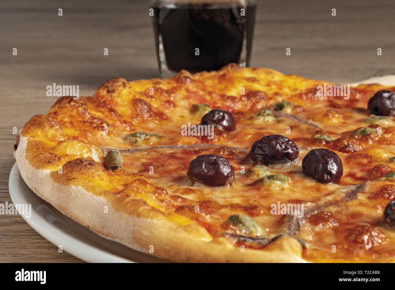 pizza pomodoro acciughe capperi olive nere intera nel piatto dal basso primo piano vista sinistra Stock Photo