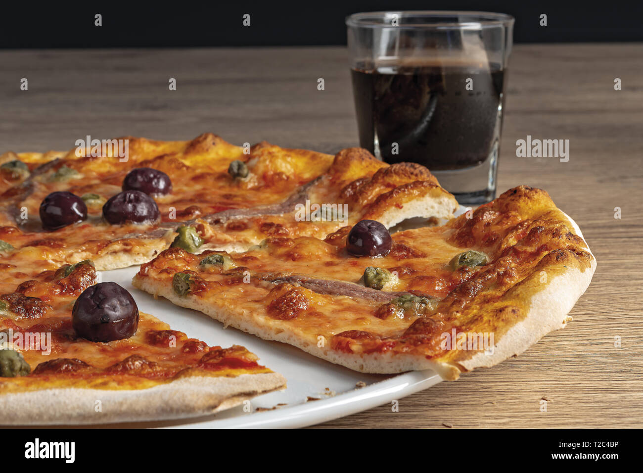 pizza pomodoro acciughe capperi olive nere tagliata nel piatto dal basso primo piano vista destra Stock Photo