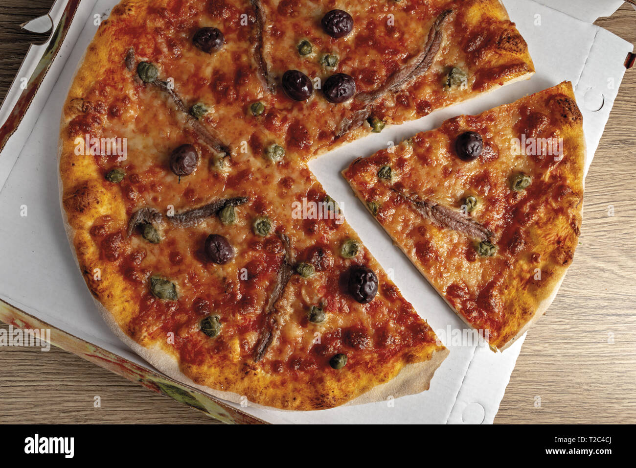 pizza pomodoro acciughe capperi olive nere tagliata dall'alto nella scatola Stock Photo