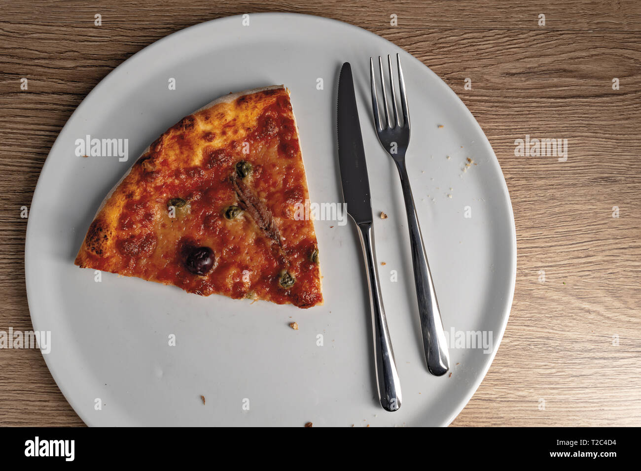 pizza pomodoro acciughe capperi olive nere fetta dall'alto nel piatto Stock Photo