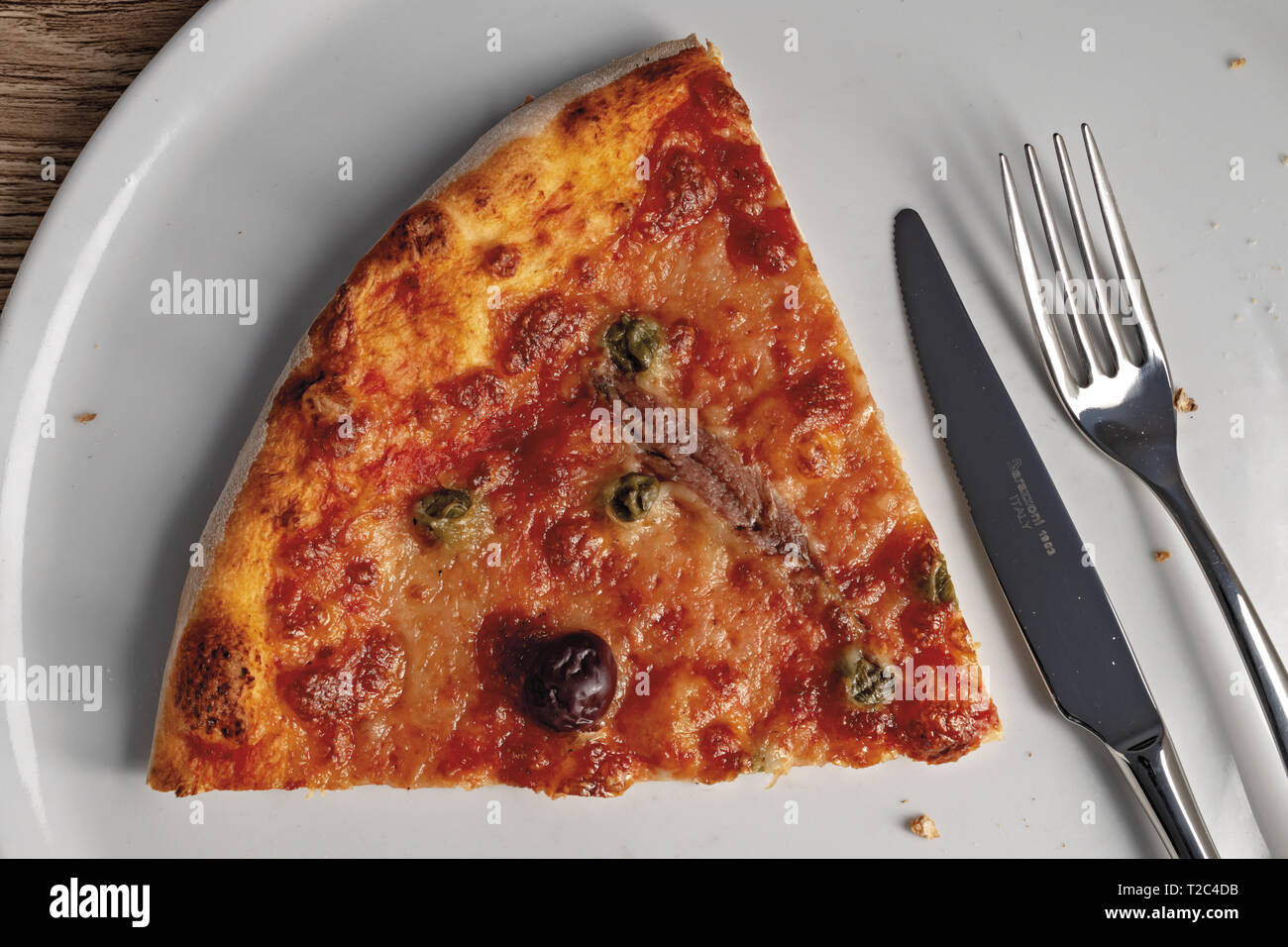 pizza pomodoro acciughe capperi olive nere fetta dall'alto nel piatto primo piano Stock Photo