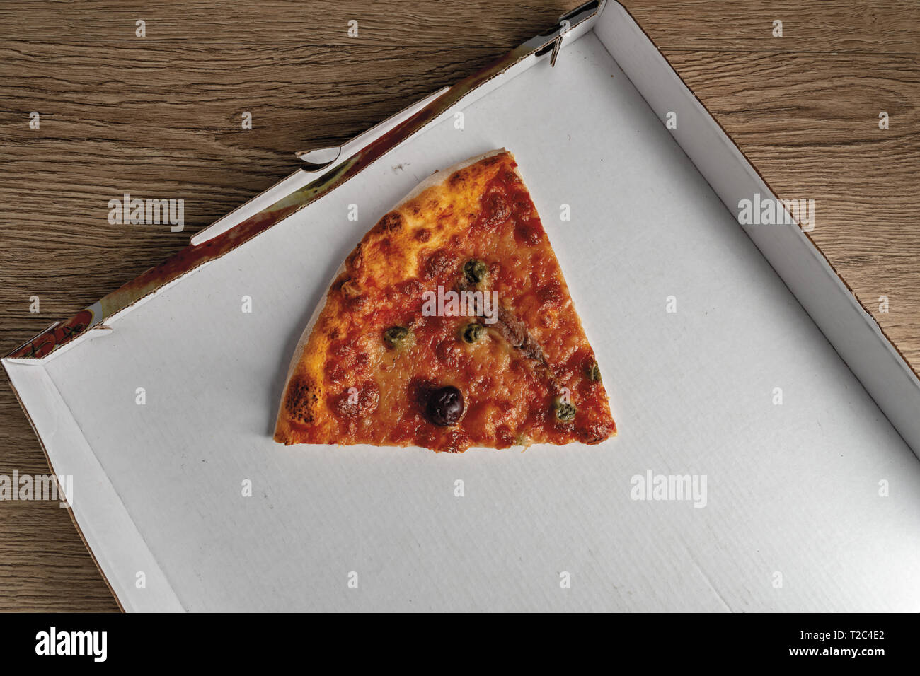 pizza pomodoro acciughe capperi olive nere fetta dall'alto nella scatola Stock Photo