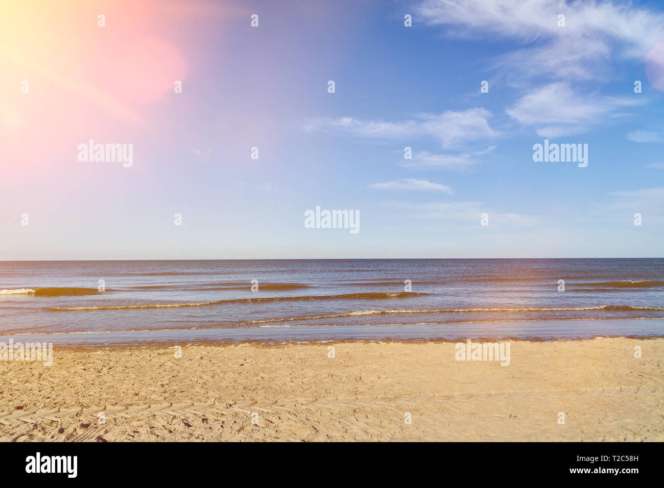 Sunny beach at the sea in front of a blue sky in summer with some white ...