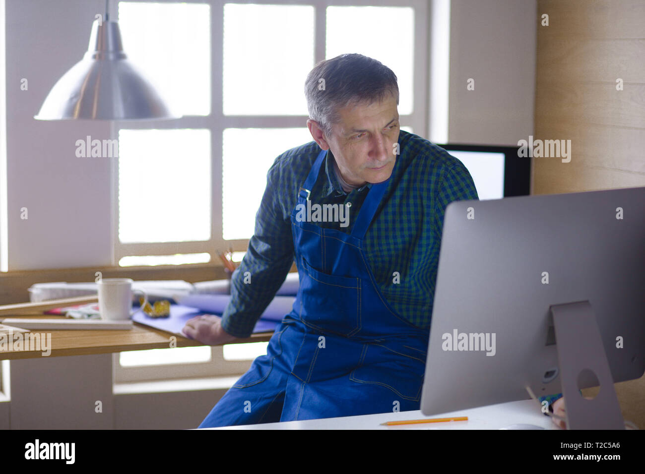 Engineer carpenter working on laptop and sketching project. Stock Photo