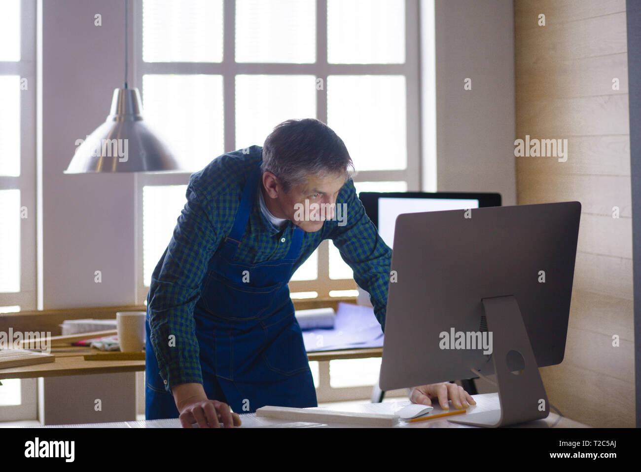 Engineer carpenter working on laptop and sketching project. Stock Photo