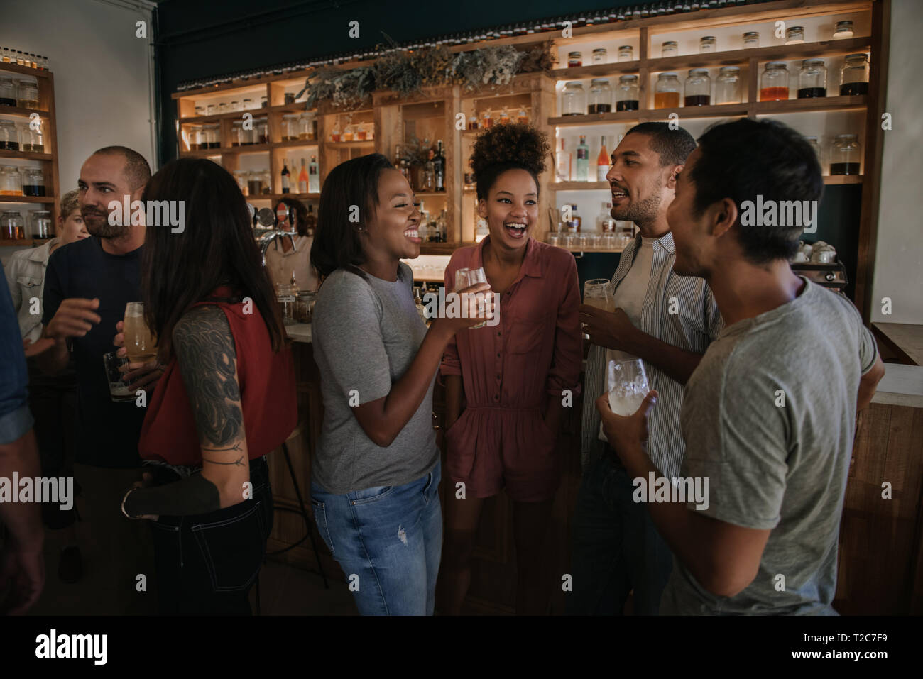 Group of diverse young friends having a fun evening out with drinks in a trendy bar Stock Photo