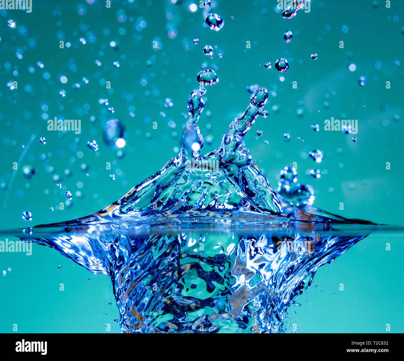 Water splash and air bubbles rise in clear water. Stock Photo