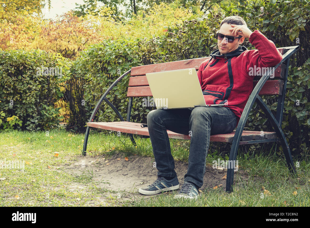 Young male student programmer work study outdoors. Programmer developer works with his laptop in the Park outside the office. Pensive man with an ultr Stock Photo