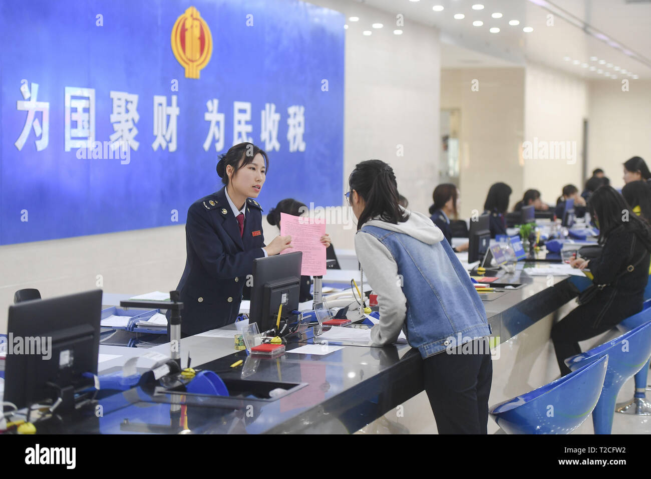 Quanzhou, China's Fujian Province. 1st Apr, 2019. A staff (L) explains to a taxpayer about a new policy on VAT reduction at a local tax bureau in Fengze District of Quanzhou, southeast China's Fujian Province, April 1, 2019. Starting on April 1, companies that are subject to the 16-percent VAT rate on their taxable sales or imported goods will enjoy a 13-percent VAT rate, while those who are subject to the 10-percent VAT rate will only need to pay 9 percent, reads a Ministry of Finance statement. Credit: Song Weiwei/Xinhua/Alamy Live News Stock Photo