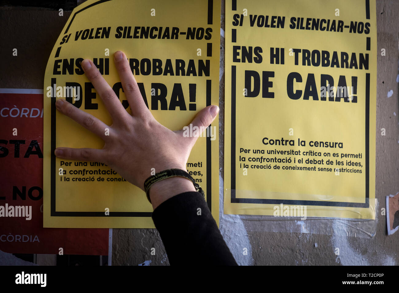 A hand is seen placing placards against censorship during the protest. As a result of the Central Electoral Board order to withdraw public space of all kinds of symbols related to the Catalan independence movement during the election period, the Union of students of the Catalan countries have hanged placards at the university campus of the UB- Raval to condemn the censure of such decision. Stock Photo