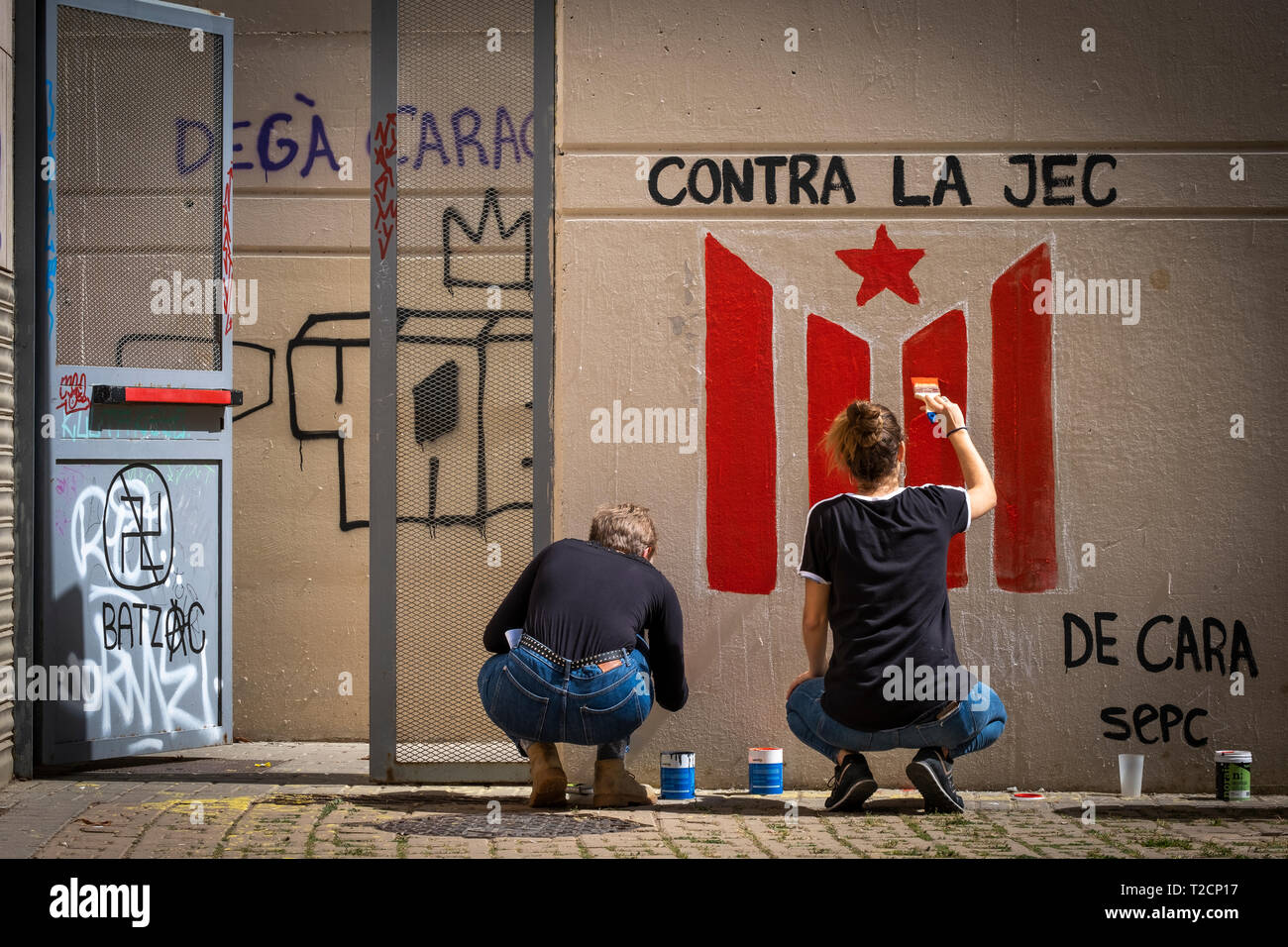 Two women are seen painting a flag of the independence of Catalonia on one of the walls at the UB-Raval during the protest. As a result of the Central Electoral Board order to withdraw public space of all kinds of symbols related to the Catalan independence movement during the election period, the Union of students of the Catalan countries have hanged placards at the university campus of the UB- Raval to condemn the censure of such decision. Stock Photo