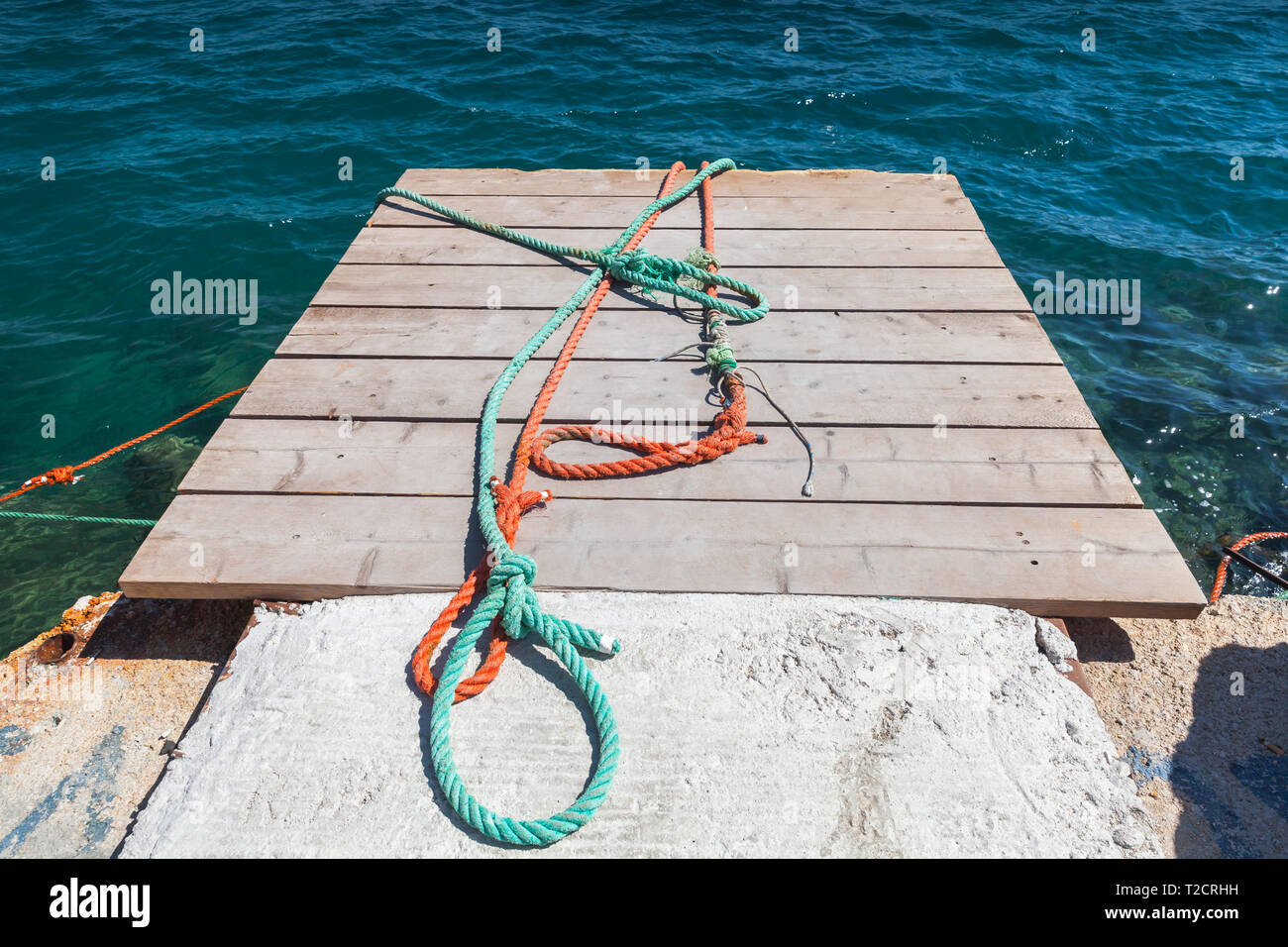 Colorful nautical ropes lay on small wooden pier. Zakynthos, Greece Stock Photo