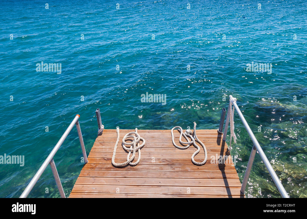 Nautical ropes lay on small wooden pier. Zakynthos island, Greece Stock Photo