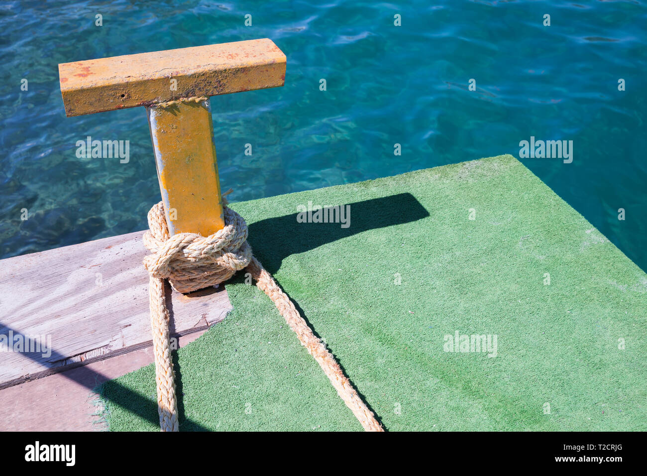 Yellow steel bollard with nautical rope on it Stock Photo