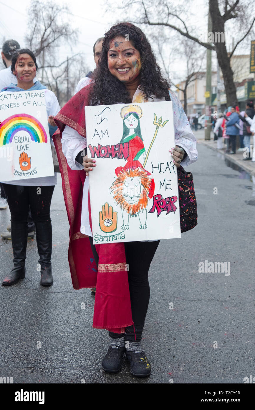 A Hindu woman marching in the Holi Parade on Liberty Ave in Richmond Hill, Queens and carrying a sign about women's pride. Stock Photo